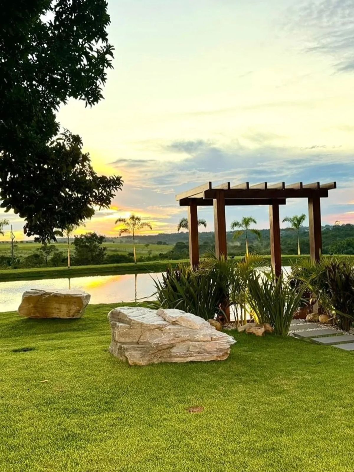 Área externa da fazenda ao entardecer com lago e pergolado