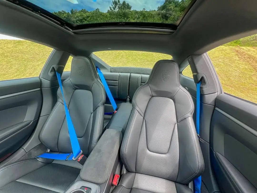 Interior traseiro do Porsche 911 com cintos azuis e teto solar