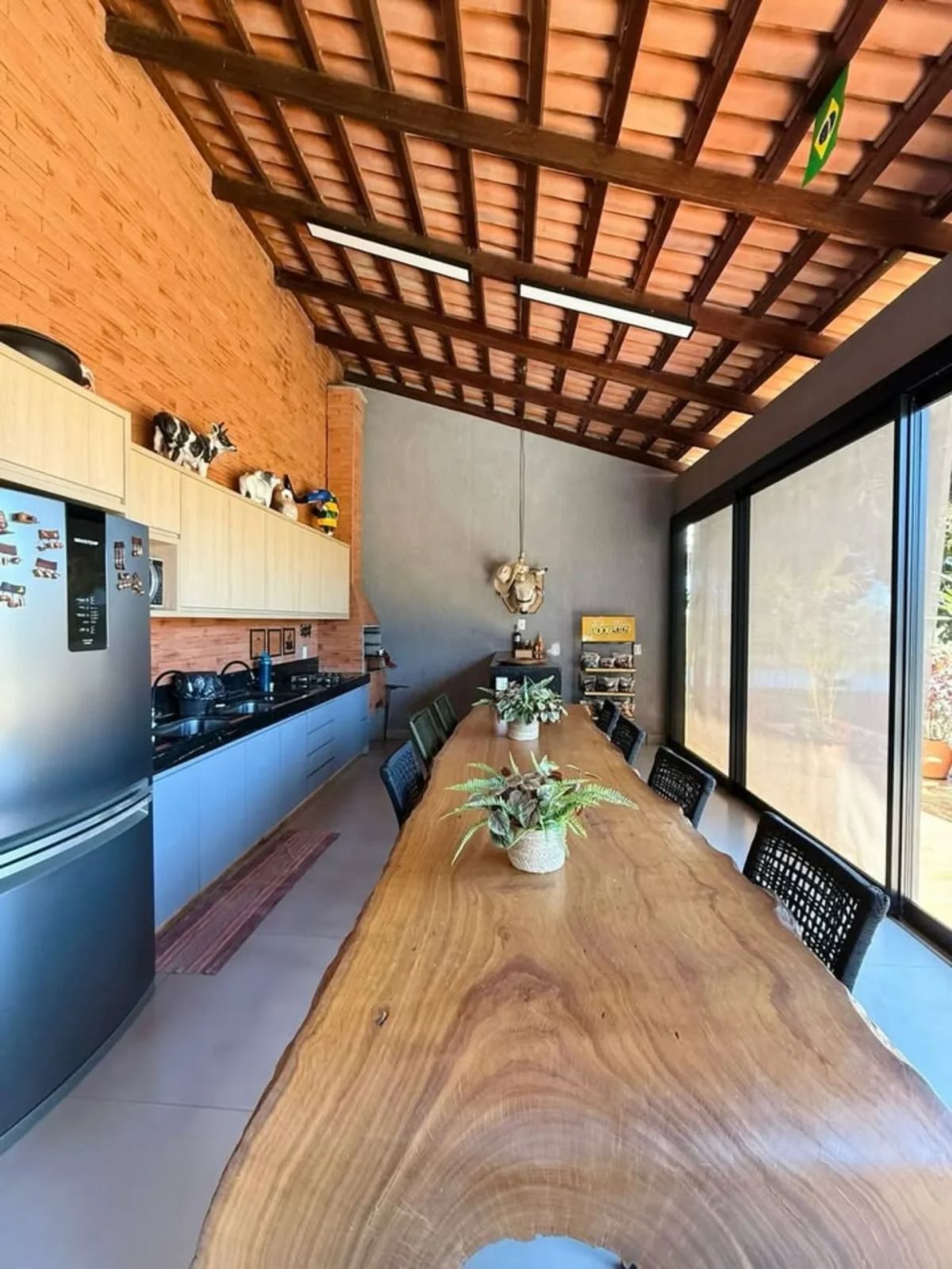 Cozinha rústica com mesa de madeira maciça e telhado aparente